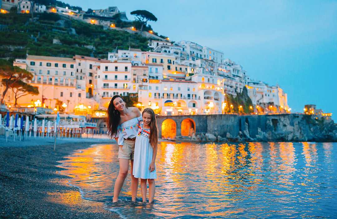 Mother and daughter on the beach at dusk in Amalfi, Italy