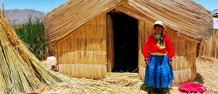A girl standing on a floating Uros island standing in front of her home in Lake Titicaca, Peru.