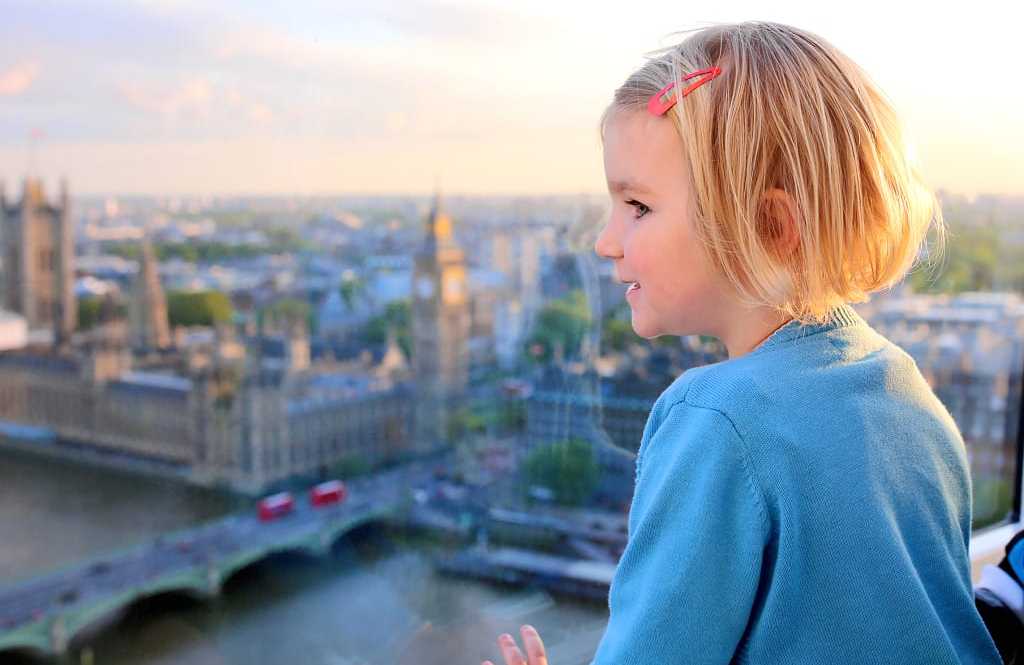 Little girl at sunset observing the Westminster Abbey in London 