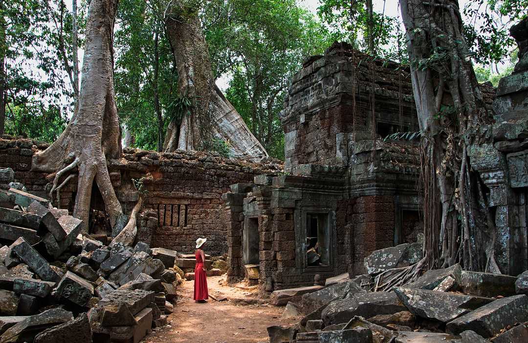 Woman in a red dress at Ta Prohm Temple ruins in Siem Reap, Cambodia