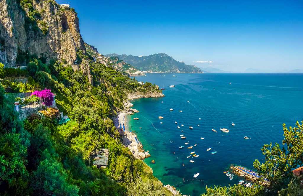 Postcard view of steep mountain cliffs and azure waters in the Amalfi Coast of Italy
