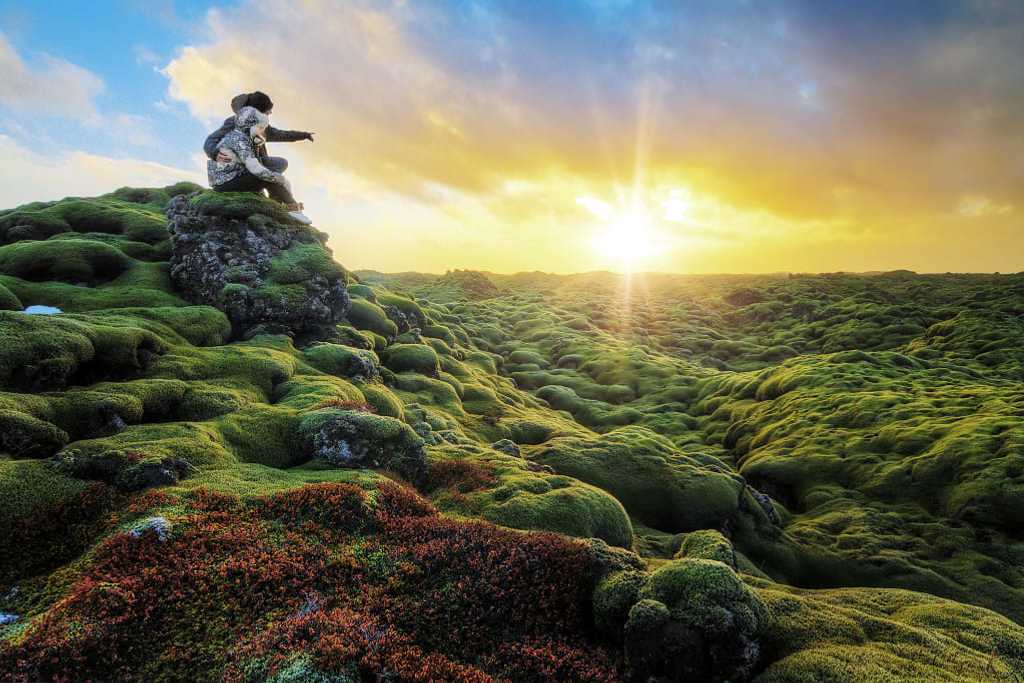 Couple watching the sunrise over Eldhraun lava field in Southern Iceland