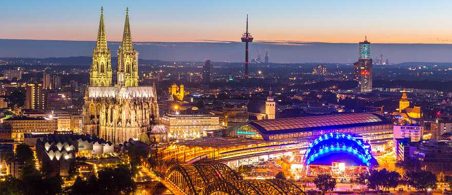 Night view of the Cologne Cathedral and the Hohenzollern bridge with the Rhine river in Germany.