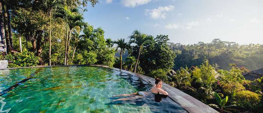 Woman lounging in an infinity pool at a luxury resort in Bali, Indonesia