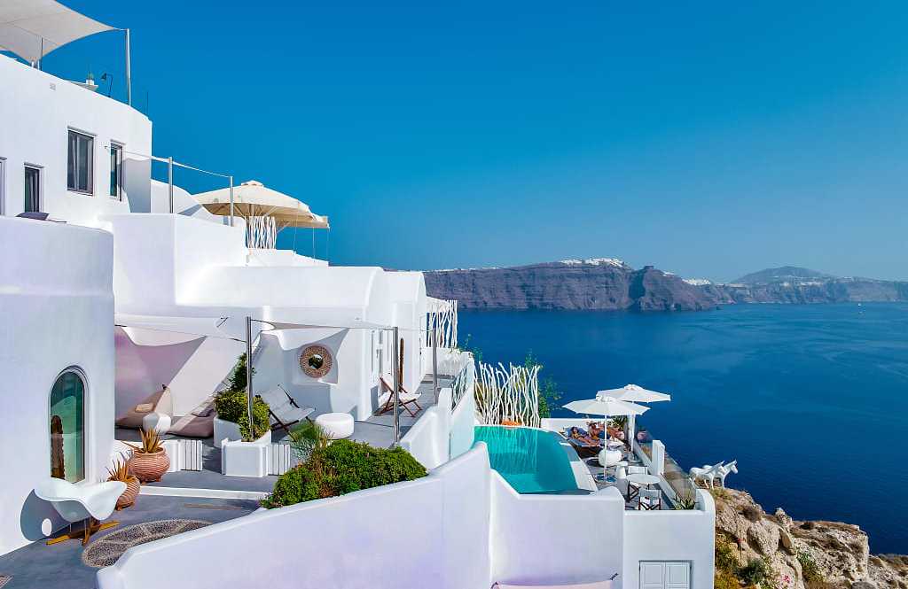 Couple lounging poolside at boutique luxury hotel in Santorini, Greece
