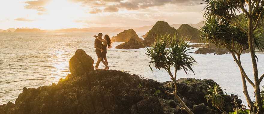 Honeymoon couple at sunset on the rock in Bali, Indonesia