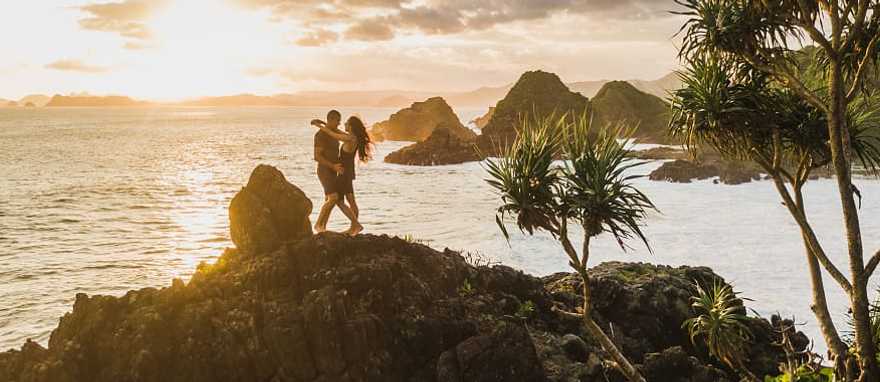 Honeymoon couple at sunset on the rock in Bali, Indonesia