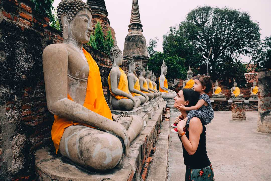 Mother and daughter looking at statues of Buddha in Ayutthaya, Thailand