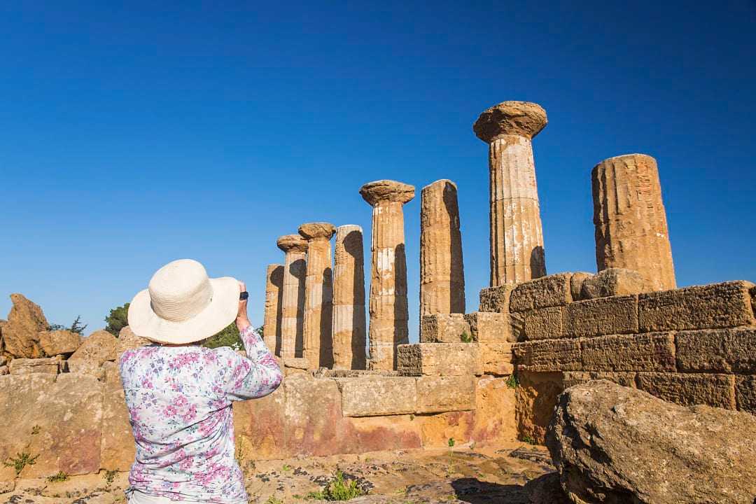 Senior woman taking a photograph at the Valley of the Temples in Sicily, Italy