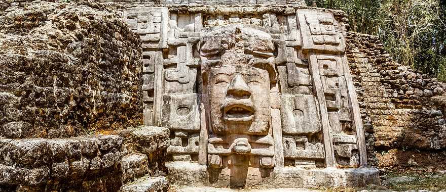 Ancient stone Mayan pre-columbian civilization pyramid with carved face in the forest, Lamanai archeological site, Orange Walk District, Belize