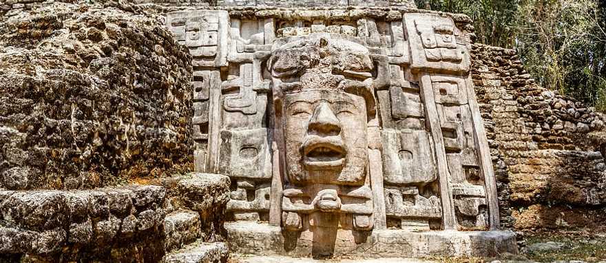 Ancient stone Mayan pre-columbian civilization pyramid with carved face in the forest, Lamanai archeological site, Orange Walk District, Belize