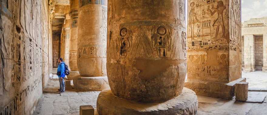 Traveler viewing hieroglyphs on the walls of the Temple of Medinet Habu in Egypt