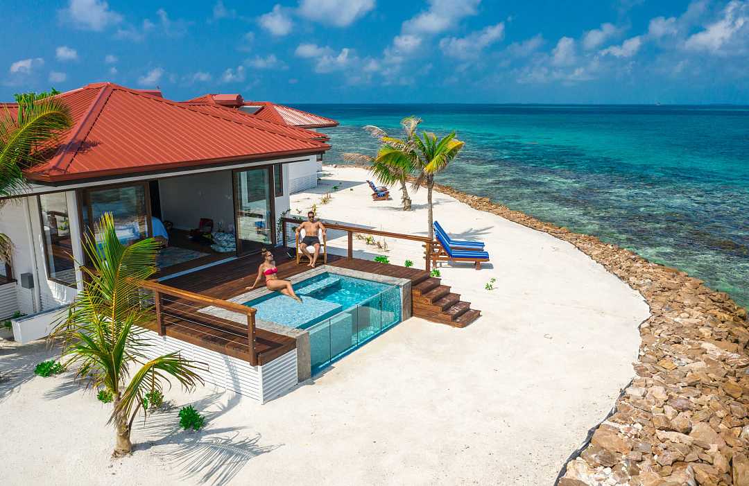 Couple at a luxury beachfront villa with a private pool, ocean view, and palm trees in Belzie